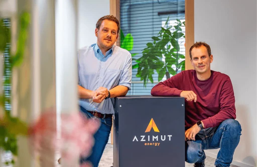Deux membres d’Azimut Energy présentant le panneau de la marque dans leurs bureaux